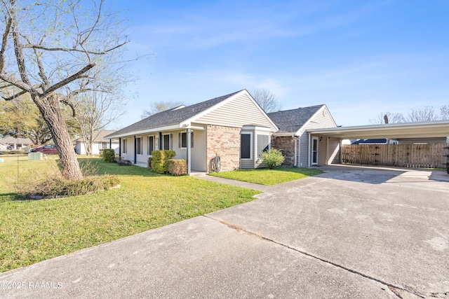 ranch-style house featuring brick siding, an attached carport, a front lawn, fence, and concrete driveway