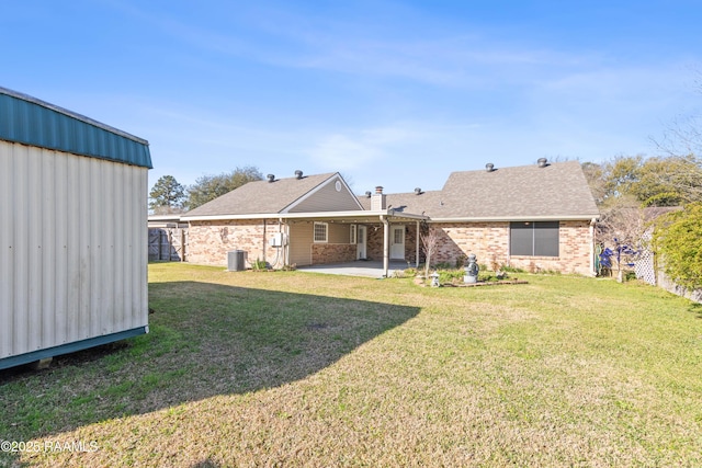 back of house featuring a yard, brick siding, a chimney, and a patio area