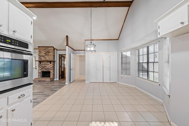 kitchen featuring oven, baseboards, light tile patterned floors, a fireplace, and white cabinets