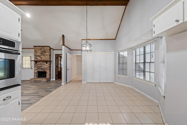 kitchen with stainless steel oven, light tile patterned flooring, crown molding, and white cabinetry