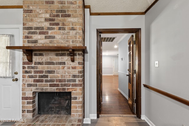 interior space featuring visible vents, a textured ceiling, wood finished floors, crown molding, and baseboards