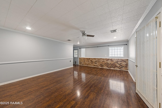 spare room with visible vents, brick wall, ceiling fan, ornamental molding, and hardwood / wood-style flooring