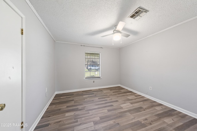 unfurnished room featuring a ceiling fan, baseboards, wood finished floors, visible vents, and ornamental molding