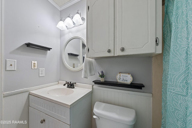 full bath with wainscoting, toilet, vanity, and ornamental molding