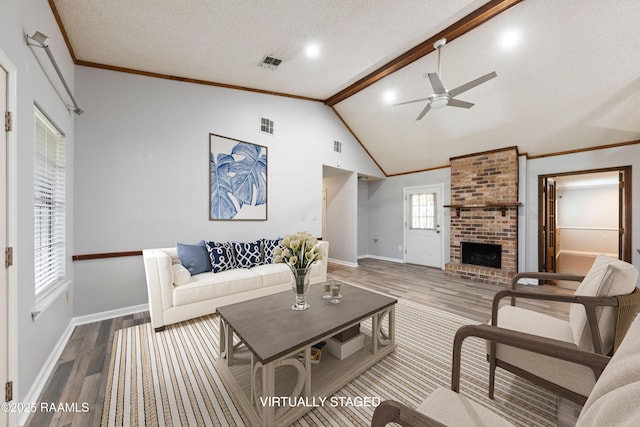 living area with visible vents, a brick fireplace, crown molding, baseboards, and wood finished floors