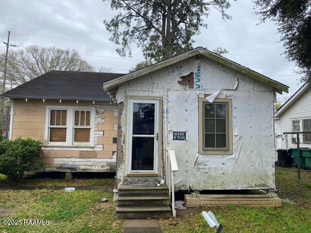 view of front facade with entry steps and roof with shingles