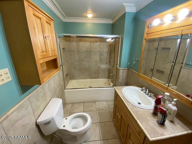 bathroom with tile patterned flooring, crown molding, and tile walls