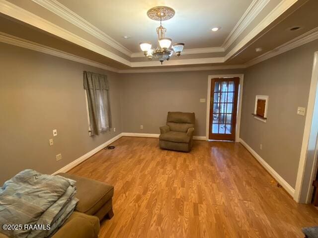 unfurnished room featuring crown molding, baseboards, a tray ceiling, an inviting chandelier, and wood finished floors