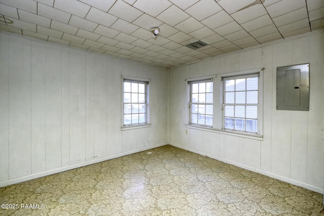 unfurnished room with electric panel, visible vents, and baseboards