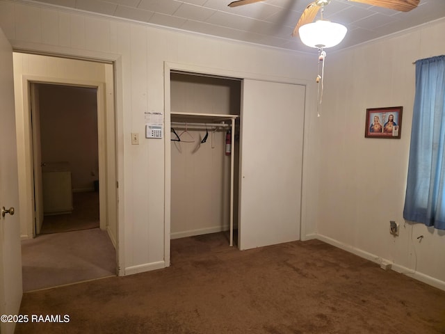 unfurnished bedroom featuring a closet, baseboards, carpet flooring, and crown molding