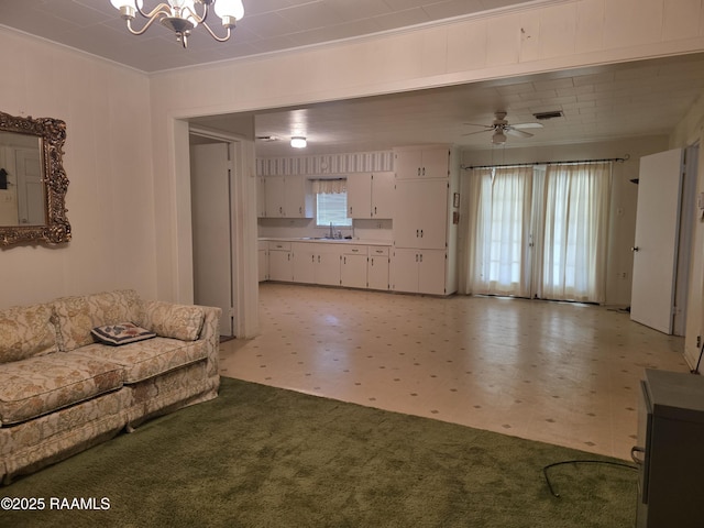 living area with visible vents, light floors, ornamental molding, and ceiling fan with notable chandelier