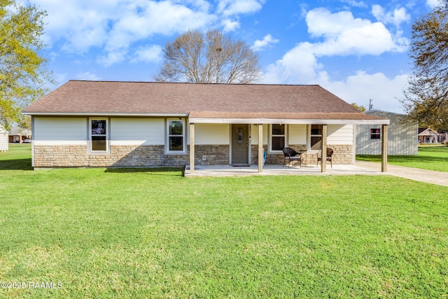 back of property with a yard, stone siding, and roof with shingles