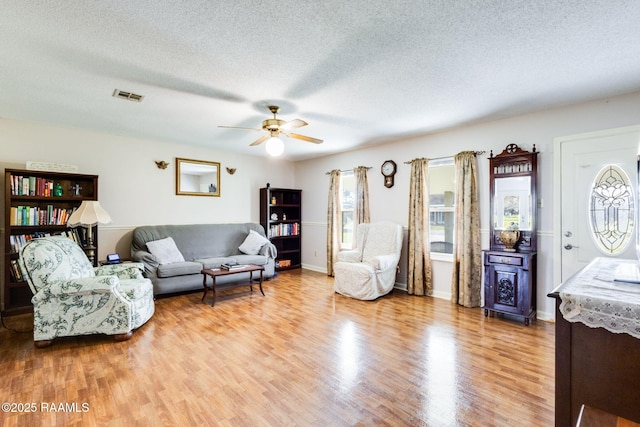 living room featuring a wealth of natural light, visible vents, a textured ceiling, and light wood-style floors