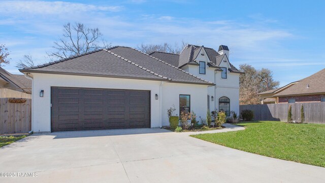 view of front of house with an attached garage, concrete driveway, a front lawn, and fence