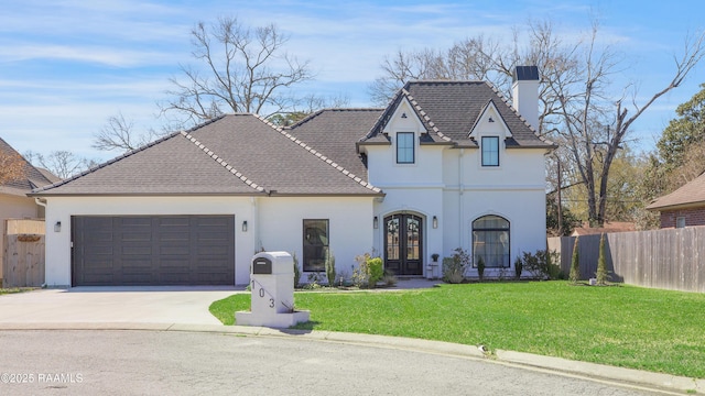 french country inspired facade featuring a front lawn, fence, french doors, driveway, and an attached garage