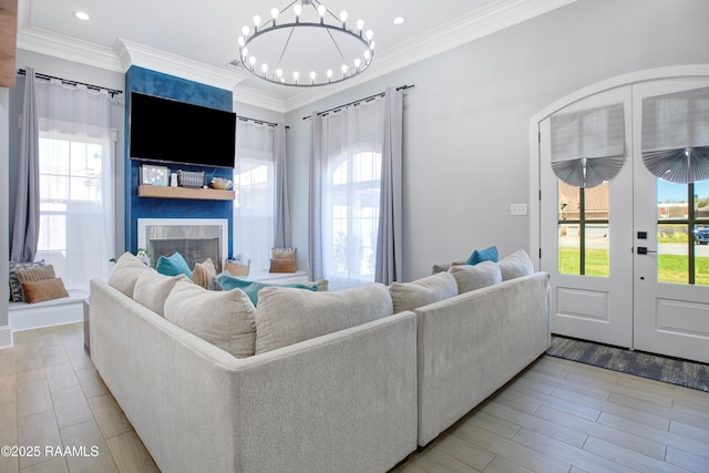 living room with a healthy amount of sunlight, french doors, a large fireplace, and ornamental molding