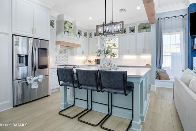 kitchen with white cabinetry, light countertops, stainless steel refrigerator with ice dispenser, and backsplash