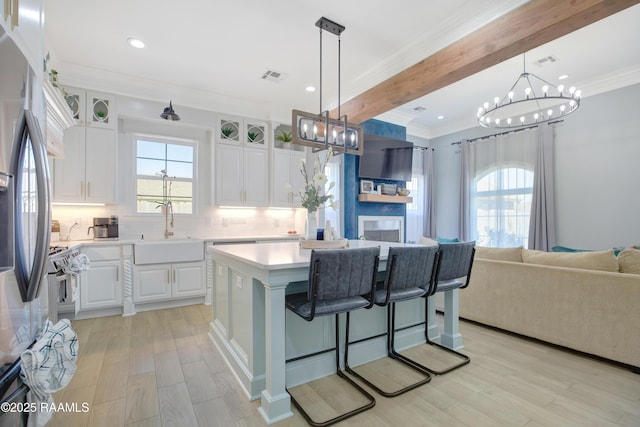 kitchen with visible vents, light countertops, open floor plan, and stainless steel refrigerator with ice dispenser