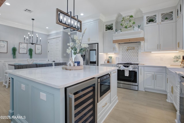 kitchen with visible vents, a center island, stainless steel appliances, wine cooler, and white cabinets