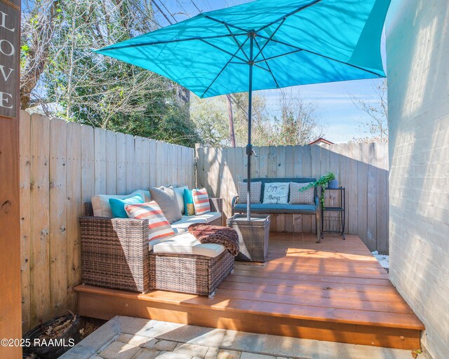 wooden terrace with an outdoor living space and a fenced backyard