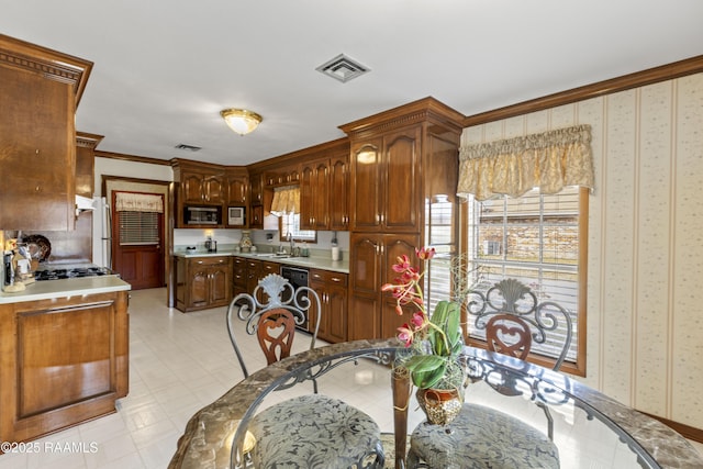 kitchen featuring visible vents, stainless steel microwave, wallpapered walls, light floors, and light countertops