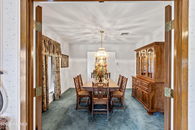 dining space featuring visible vents, a notable chandelier, ornamental molding, and dark carpet