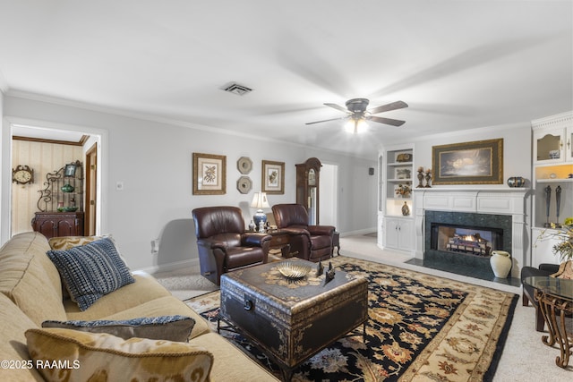 carpeted living area with built in shelves, baseboards, visible vents, a fireplace, and ornamental molding