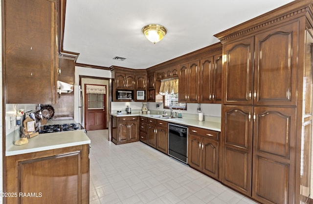 kitchen featuring stainless steel microwave, visible vents, dishwasher, light countertops, and a sink