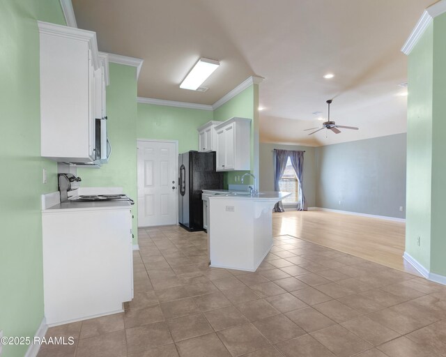 kitchen featuring a ceiling fan, freestanding refrigerator, white cabinetry, crown molding, and open floor plan