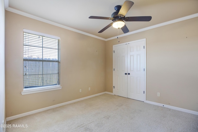 unfurnished bedroom featuring a ceiling fan, a closet, carpet, crown molding, and baseboards