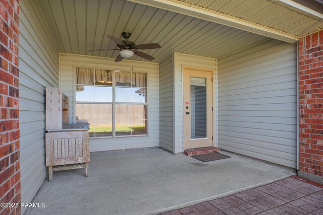 view of exterior entry with brick siding and ceiling fan