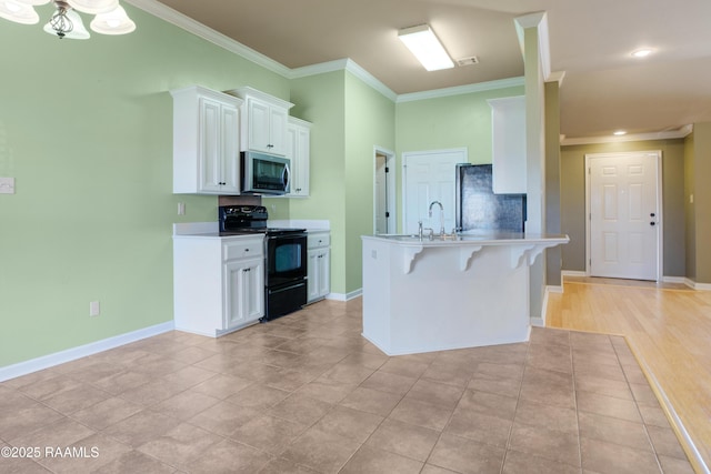 kitchen with a kitchen bar, ornamental molding, black electric range oven, stainless steel microwave, and white cabinetry