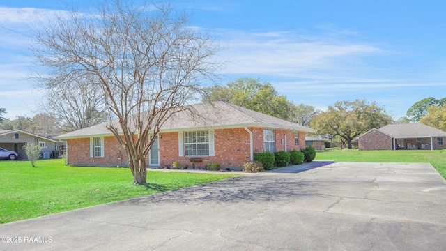 view of front of house featuring driveway, brick siding, and a front yard