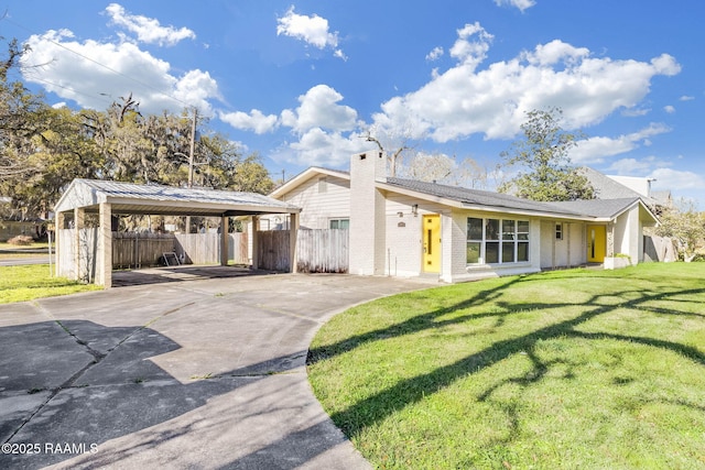 view of front facade featuring a detached carport, a front lawn, fence, a chimney, and driveway