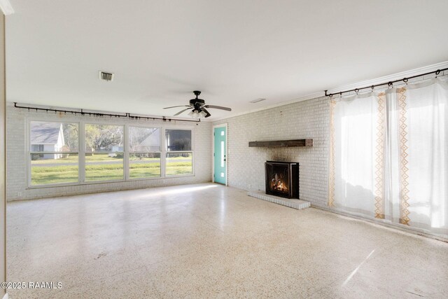 unfurnished living room with visible vents, speckled floor, brick wall, ceiling fan, and a brick fireplace