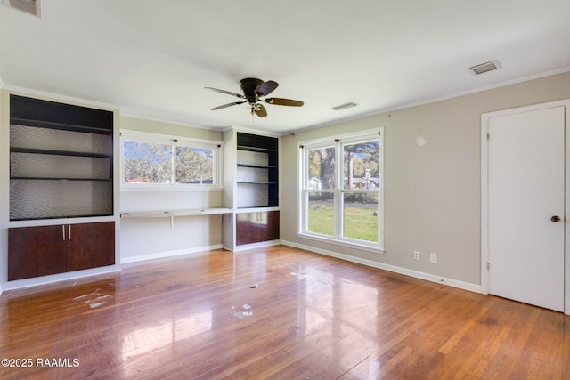 unfurnished living room featuring ornamental molding, wood finished floors, baseboards, and a healthy amount of sunlight