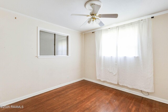 empty room with a ceiling fan, crown molding, baseboards, and wood finished floors