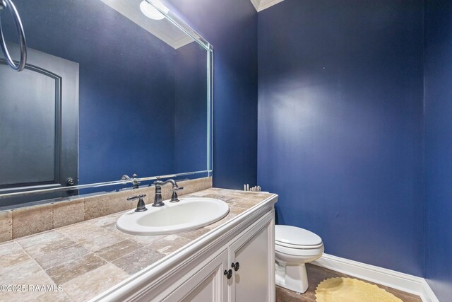 bathroom with toilet, vanity, and baseboards