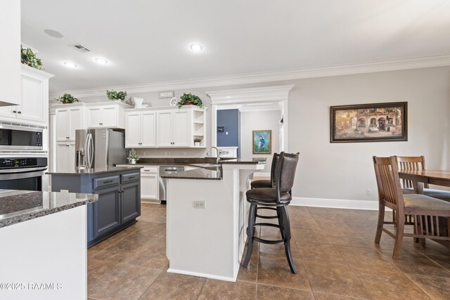 kitchen with a kitchen bar, open shelves, white cabinets, and appliances with stainless steel finishes