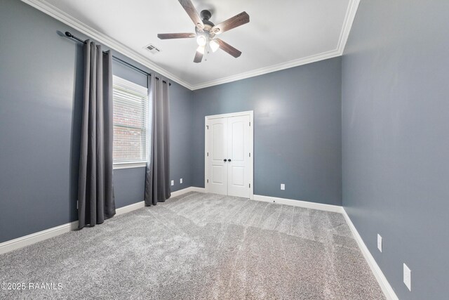 unfurnished bedroom featuring visible vents, crown molding, baseboards, carpet flooring, and a ceiling fan