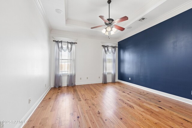 unfurnished room featuring baseboards, visible vents, ornamental molding, wood-type flooring, and a raised ceiling