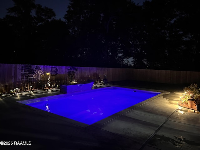 pool at night with a fenced in pool, a patio, and a fenced backyard