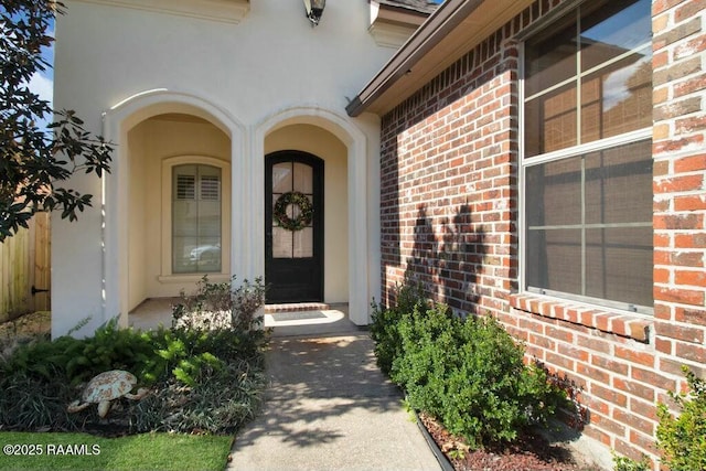 property entrance with brick siding and stucco siding