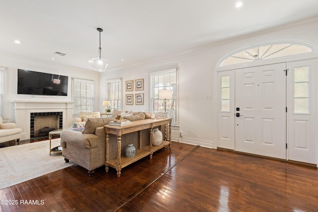 living room featuring dark wood-style floors, visible vents, a healthy amount of sunlight, and crown molding