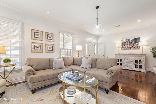 living room with hardwood / wood-style flooring, a healthy amount of sunlight, visible vents, and ornamental molding