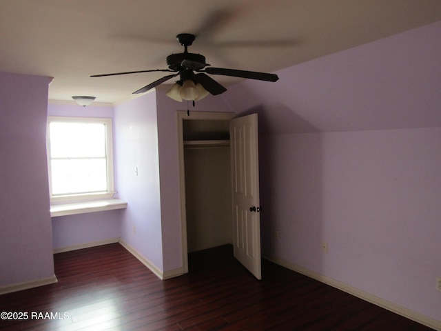 unfurnished bedroom with a ceiling fan, a closet, baseboards, dark wood-style flooring, and vaulted ceiling