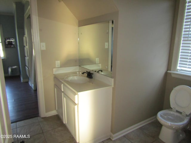 bathroom with tile patterned flooring, toilet, vanity, and vaulted ceiling