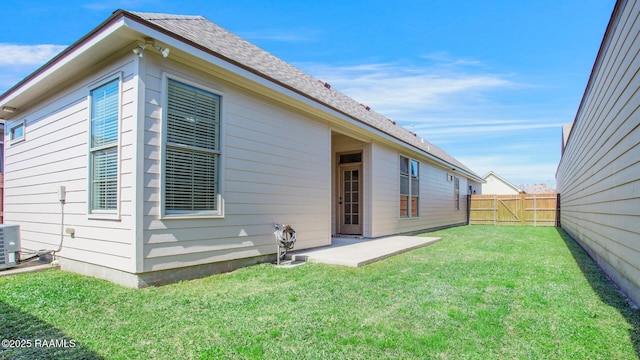 rear view of property featuring a yard, a patio, roof with shingles, and a fenced backyard