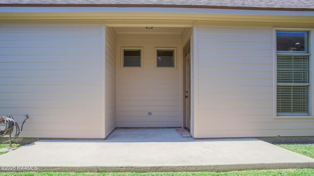 view of exterior entry featuring roof with shingles