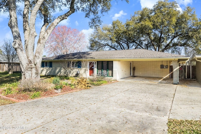 ranch-style home with an attached carport, concrete driveway, fence, and brick siding